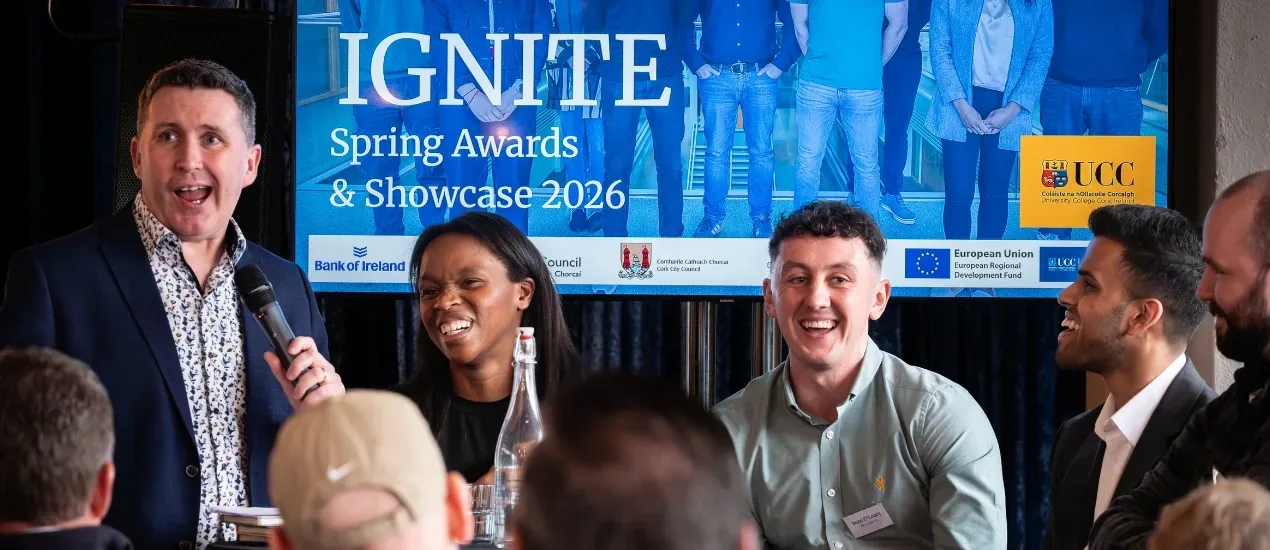 Image of 4 people sitting laughing in front of a seated audience