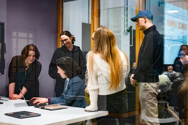 Image of 4 people standing together looking at a laptop