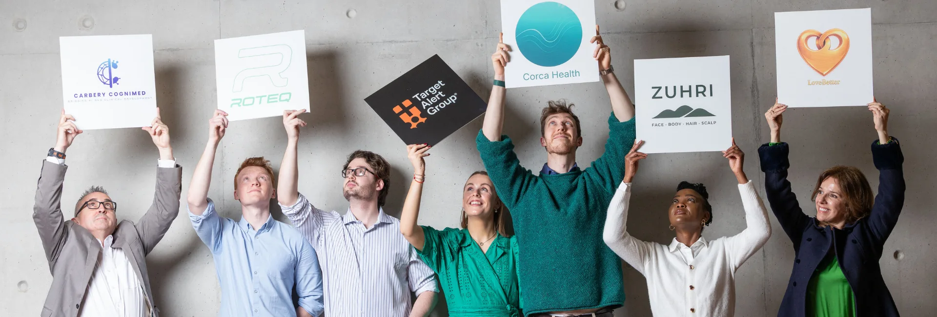 Image of 7 people holding up signs with the names of their start-up business