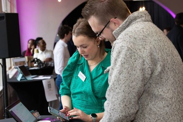 Two people standing and looking at a phone