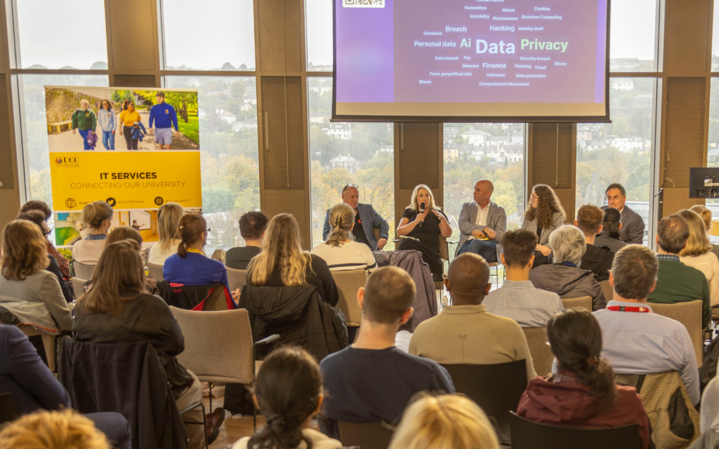 An image of an event with a panel of speakers and an audience in the Dora Allman Room in UCC