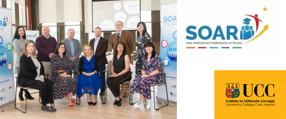 Male and female colleagues of the SOAR project in seated and standing rows pose beside SOAR project pull-up stands