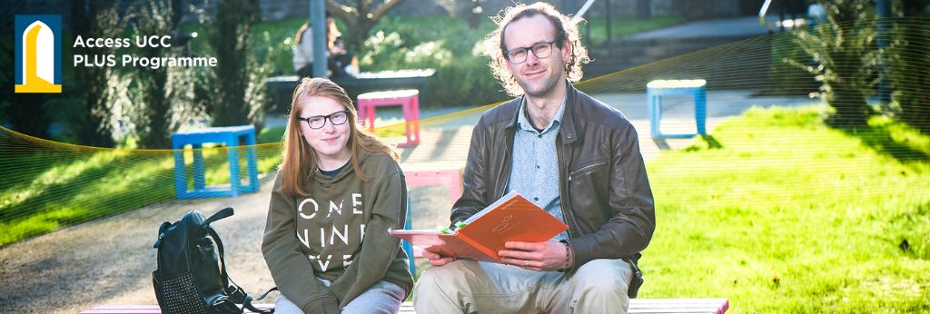 PLUS Programme Decretive Banner |  Two students sitting in the grounds of UCC