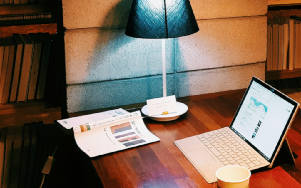 A desktop with lamp, laptop, coffee and book
